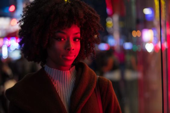 Model in white turtleneck and brown coat at night