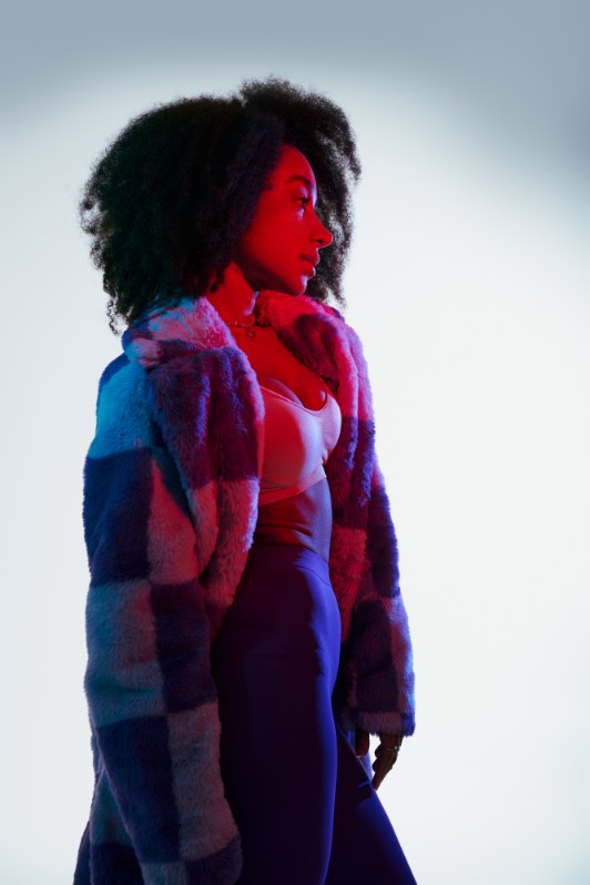 Profile in checkered fur coat under red and blue light