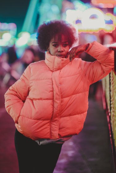 Model in coral puffer jacket under city lights